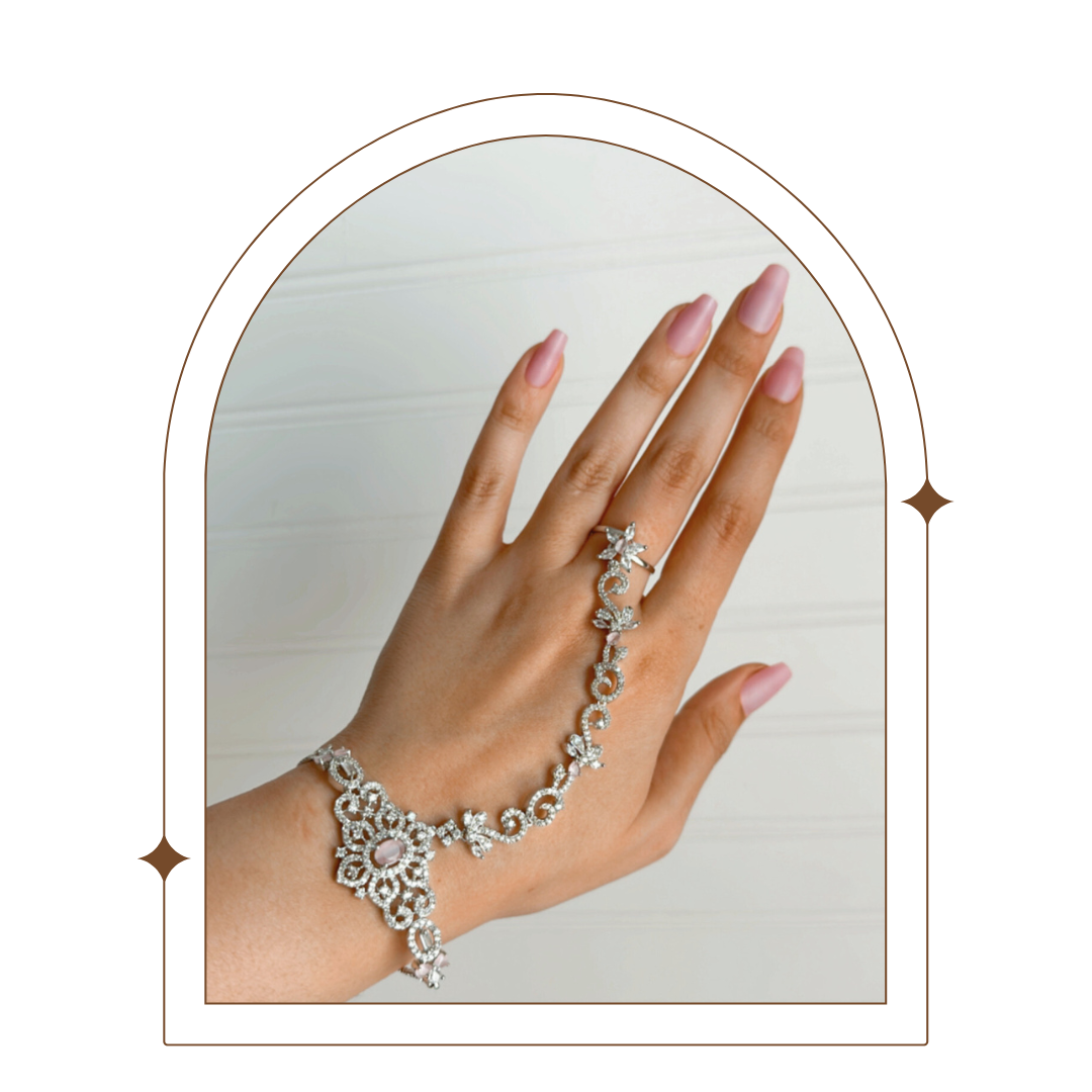 Close-up of a luxurious hand chain featuring intricate silver-plated design with sparkling stones, combining a ring and bracelet on a hand with manicured nails. Perfect for adding elegant style and unique charm.