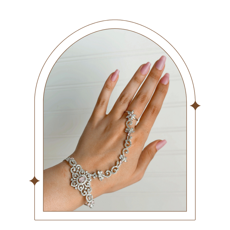 Close-up of a luxurious hand chain featuring intricate silver-plated design with sparkling stones, combining a ring and bracelet on a hand with manicured nails. Perfect for adding elegant style and unique charm.